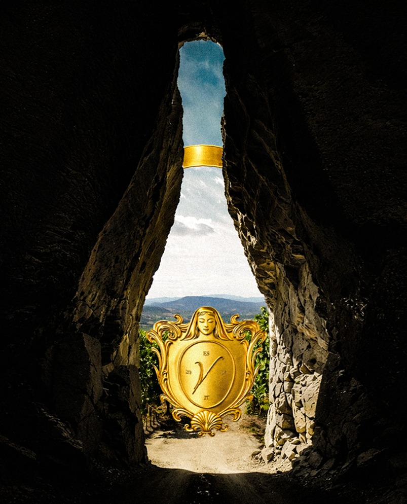 Rocky cavern archway shaped like a bottle, with the glowing gold VERE medallion framing the vineyard view